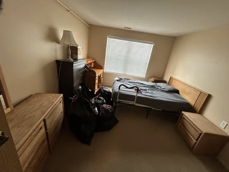 Before bedroom junk removal in Lubbock TX showing a bed covered with junk and clutter inside a residential room