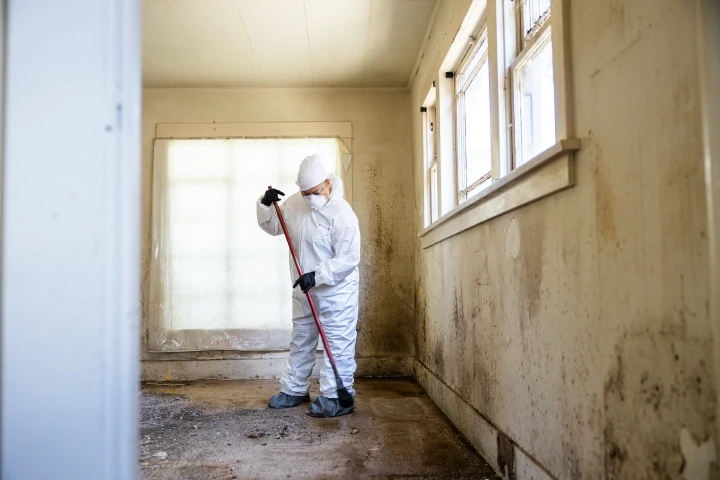 Worker in protective gear cleaning an empty room after a hoarding cleanup in Lubbock, TX