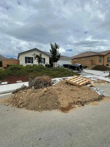 Construction Debris Removal pile with dirt, concrete chunks, and wood planks on a residential street